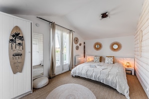A bedroom with a bed, a window with curtains, a wall with decorative plates, and a surfboard decoration. - Eleuthera Guest Room with Lake View, Shared Pool and Wi-Fi (Gujan-Mestras)