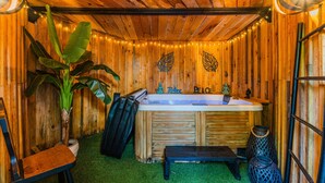 A wooden cabin with a hot tub, a bench, and a large plant. - Eleuthera Guest Room with Lake View, Shared Pool and Wi-Fi (Gujan-Mestras)