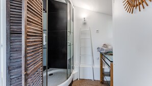 A bathroom with a glass shower enclosure, a wooden slatted door, a white ladder, and a towel rack. - Eleuthera Guest Room with Lake View, Shared Pool and Wi-Fi (Gujan-Mestras)