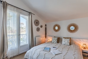 Ein Schlafzimmer mit Bett, einem Fenster mit Vorhängen, einem Heizkörper und Wanddekorationen.
