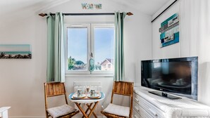 A room with a television, two chairs, a table with drinks, a window with curtains, and a 'Welcome' sign. - Bed and Breakfast 'Makatea' with Shared Pool, Shared Garden and Wi-Fi (Gujan-Mestras)