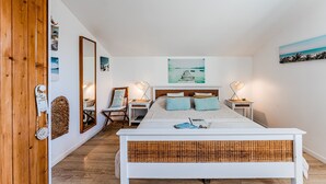 A bedroom with a bed, bedside tables, a mirror, a wall-mounted artwork, and a wooden wardrobe. - Bed and Breakfast 'Makatea' with Shared Pool, Shared Garden and Wi-Fi (Gujan-Mestras)