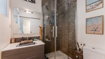 A modern bathroom with a glass shower enclosure, a sink with a towel, and a toilet.