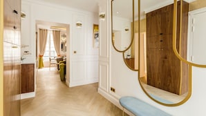 Un corridoio d'hotel con pavimento in legno, una panca, uno specchio con cornice dorata e, sullo sfondo, una sala da pranzo.