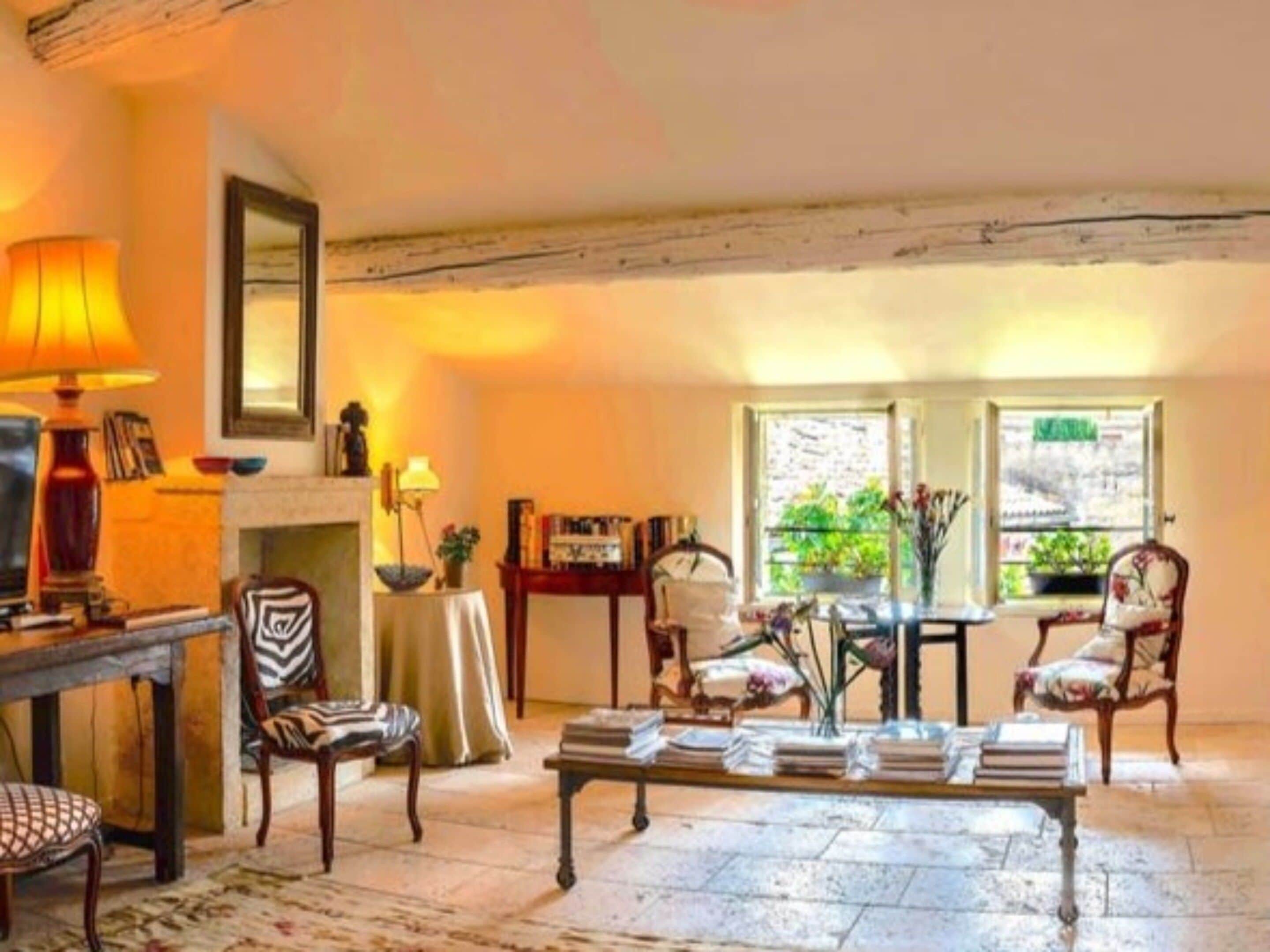 A cozy living room with a fireplace, a table with books, and a comfortable seating area.