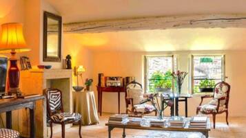 A cozy living room with a fireplace, a table with books, and a comfortable seating area.