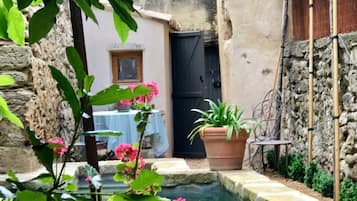 Un patio estrecho con una piscina pequeña, plantas en macetas y una mesa con mantel.