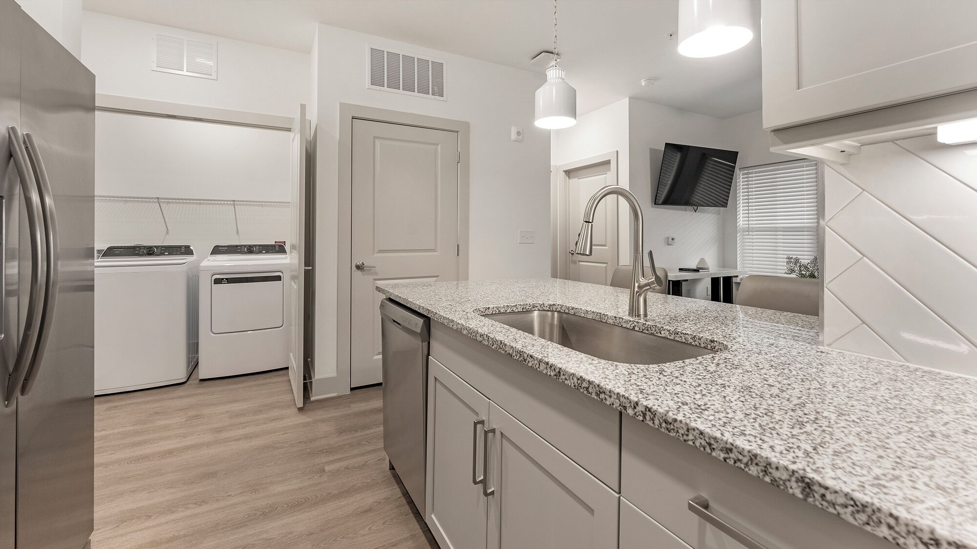 A modern kitchen with a granite countertop, stainless steel appliances, and a built-in dishwasher.