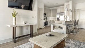 Een moderne keuken met witte kasten, roestvrijstalen apparatuur en een eethoek met een tafel en stoelen.