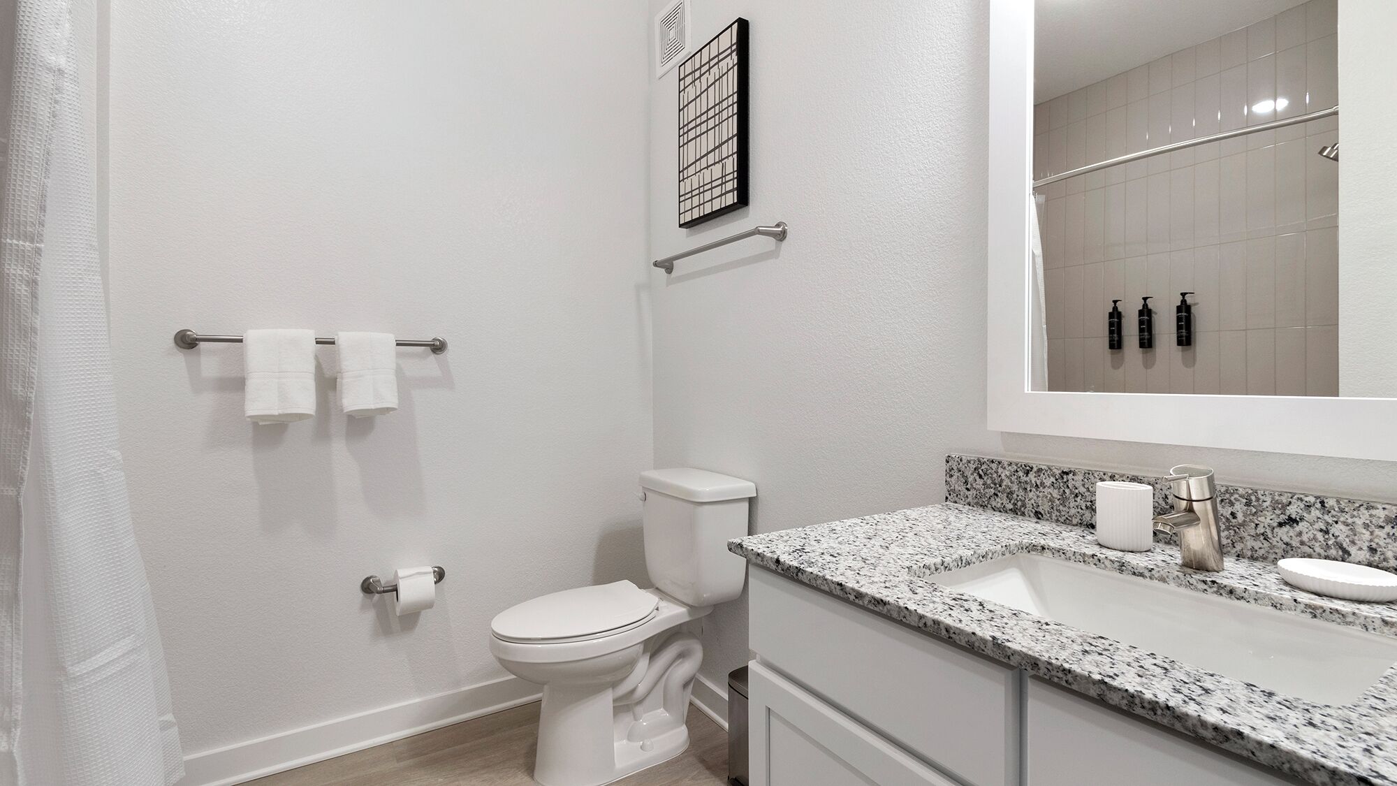 A modern bathroom with a toilet, sink, and mirror.