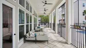 A covered outdoor area with seating, ceiling fans, and a view of a pool. - Landing Apartments near JAX (Jacksonville)