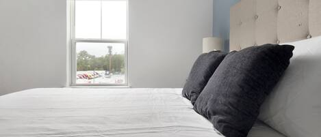 A bedroom with a large bed, a window with a view of parked trucks, and a tufted headboard.