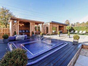 Eine Holzterrasse mit Whirlpool, Sitzgelegenheit und einer Schaukel.
