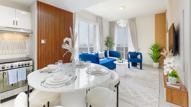 A modern kitchen with white cabinets, a stainless steel stove, and a dining area with a round table set for four.
