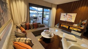 Una sala moderna con un sofá seccional, una mesa de centro y una chimenea. Hay un ventanal que ofrece vistas al exterior.
