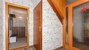 A room with a white brick wall, a wooden door, and a large window with a red star decoration.