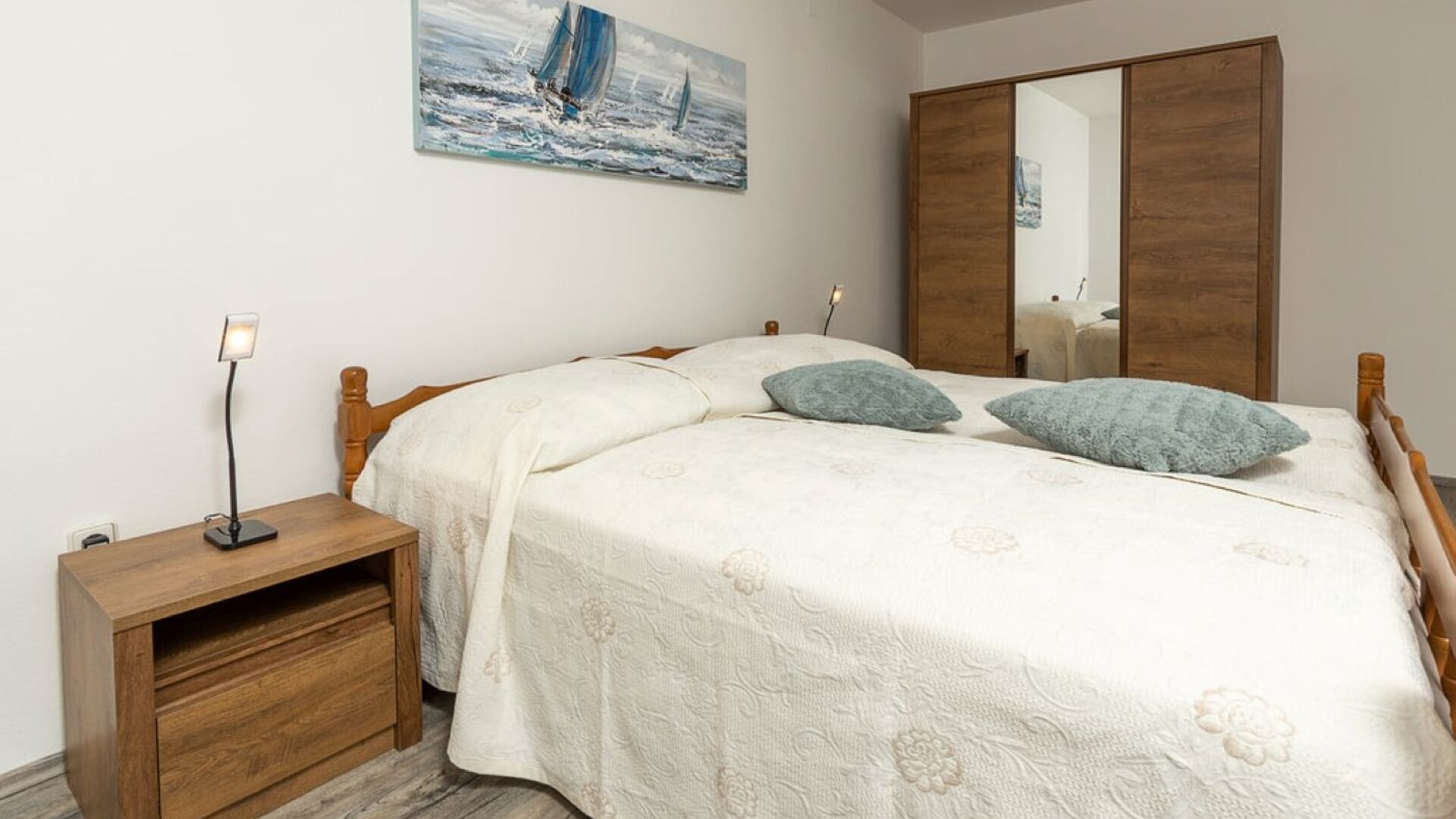 Une chambre à coucher avec un lit, une table de chevet, une commode et un tableau accroché au mur.