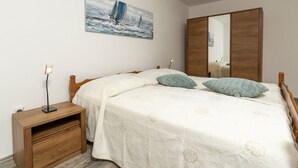 Een slaapkamer met een bed, nachtkastje en een schilderij aan de muur.