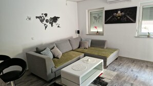 Een moderne woonkamer met een grijze bank, een witte salontafel en een wereldkaart aan de muur.
