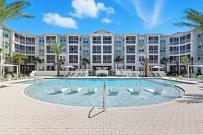A hotel with a large pool, multiple balconies, and palm trees. - Landing Apartments Downtown Palm Coast (Palm Coast)