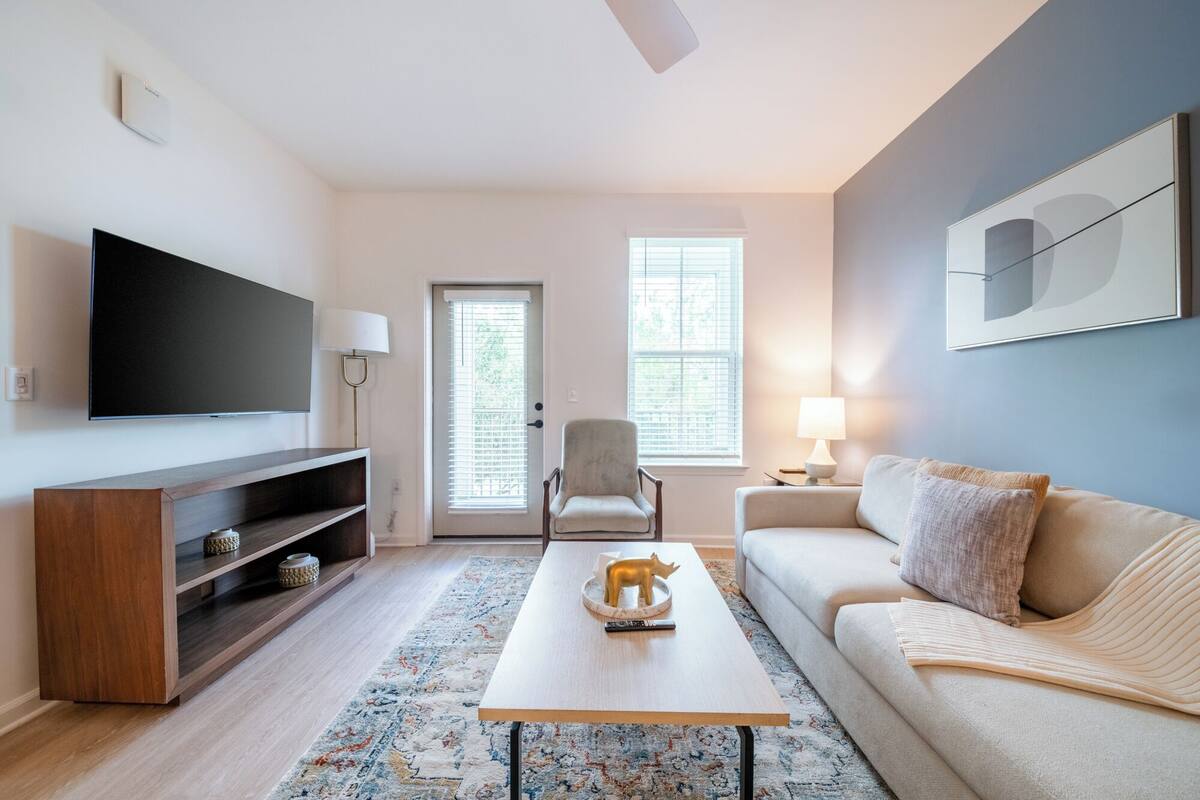 A modern living room with a flat-screen TV, a sofa, a coffee table, and a chair.