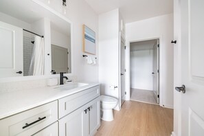 A modern bathroom with a white sink, mirror, and toilet. - Landing Apartments Downtown Palm Coast (Palm Coast)