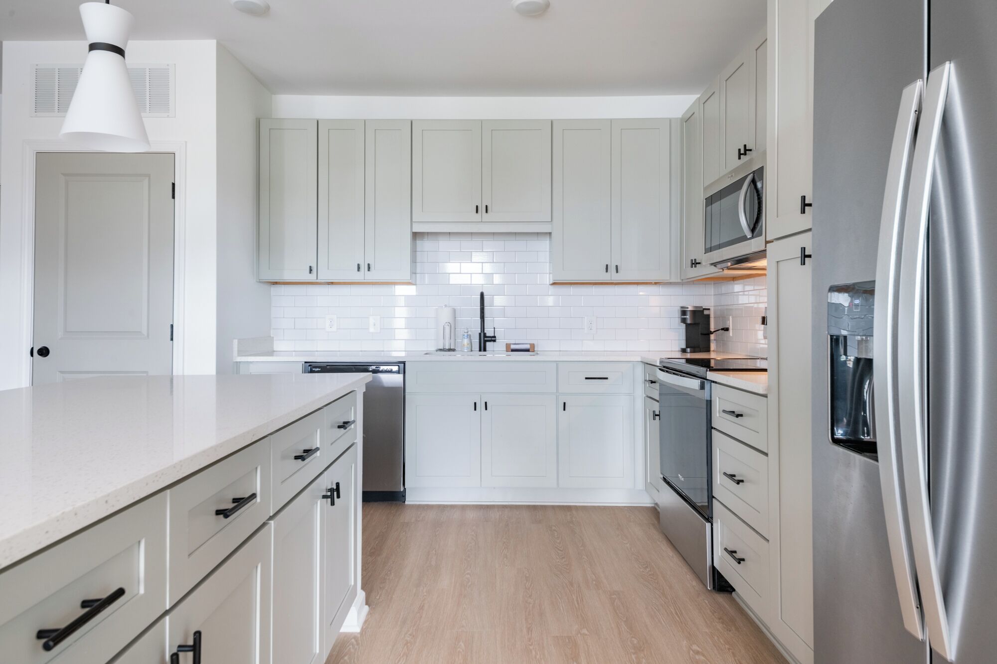 Una cocina moderna con armarios blancos, un refrigerador de acero inoxidable y un lavavajillas.