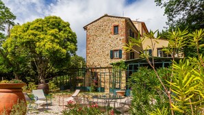 A stone building with a garden patio, outdoor seating, and a large tree. - 'Ficaiola' Room with Shared Pool and Garden (Massa Marittima)