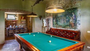 A pool table with a green felt surface, a wooden bench with a decorative backrest, and a mural on the wall. - 'Ficaiola' Room with Shared Pool and Garden (Massa Marittima)