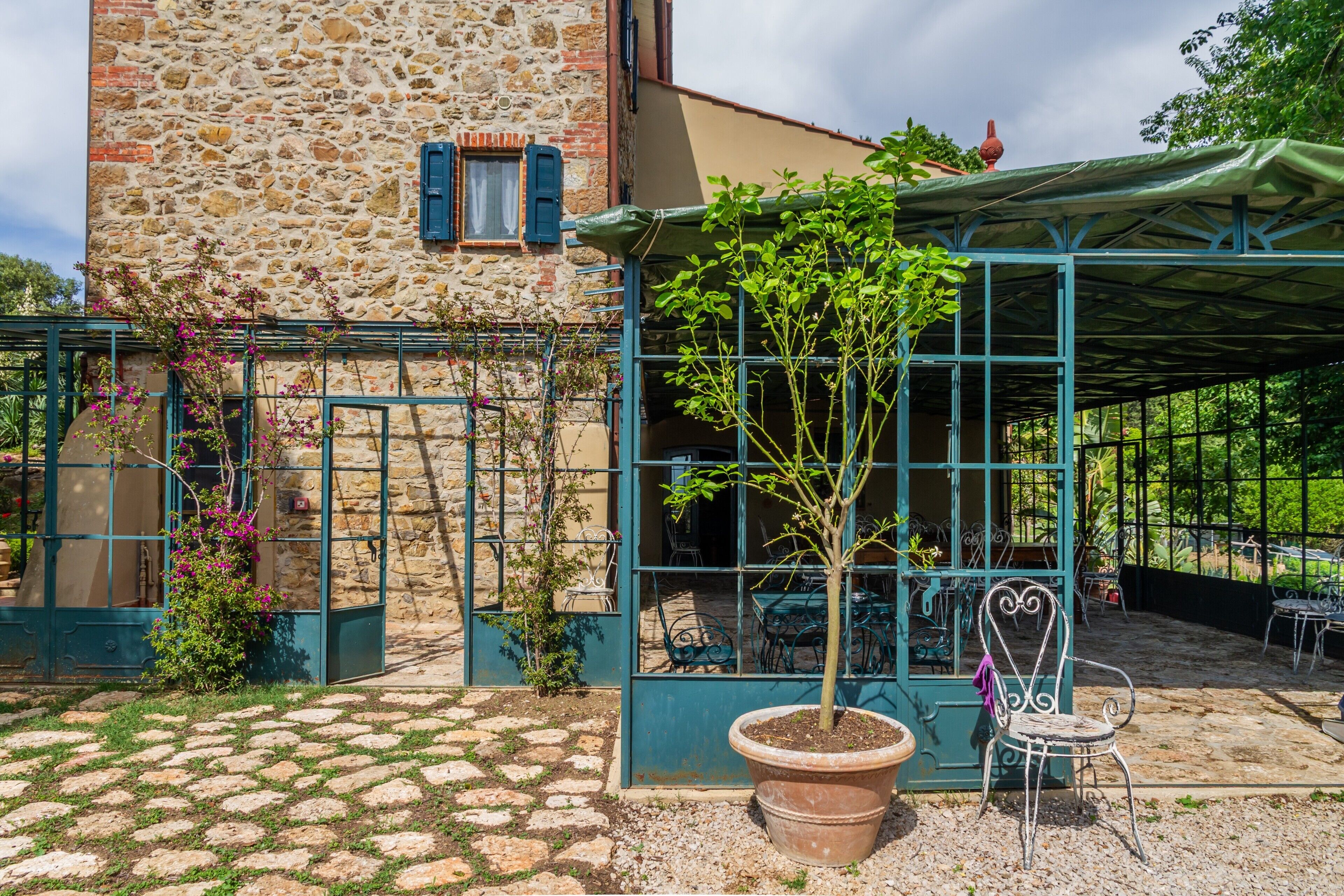 A stone building with a covered patio, potted plants, and outdoor furniture.