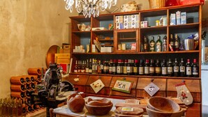 A kitchen with wooden shelves stocked with bottles, a wine press, and various kitchen utensils. - 'Corbellino' Room with Shared Pool and Garden (Massa Marittima)