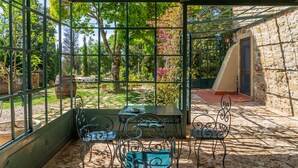 A covered outdoor area with a table and chairs, surrounded by stone walls and greenery. - 'Cuculino' Room with Shared Pool and Garden (Massa Marittima)