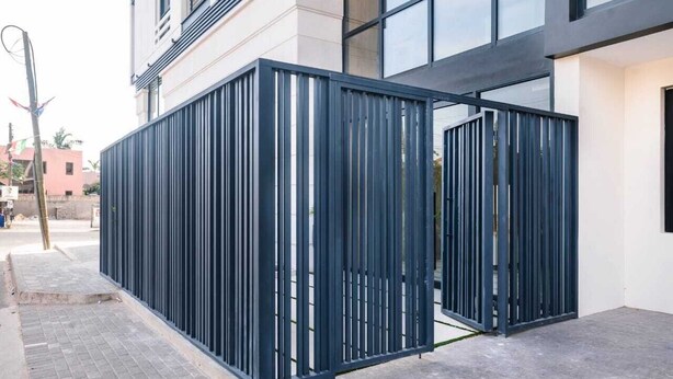 Un bâtiment moderne avec une clôture en métal à l’avant.