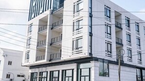 Un immeuble moderne à plusieurs étages, doté de balcons, de grandes fenêtres et d’un toit plat.