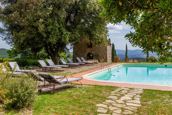 A pool area with lounge chairs, a stone pathway, and a view of the landscape.