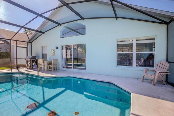 Ein überdachter Poolbereich mit Glasveranda, Grillmöglichkeit und Gartenmöbeln.