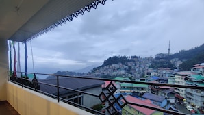 A balcony with a view of a hillside town, including a prominent tower. - Keswani Group Tashi Heritage Hotel (Gangtok)