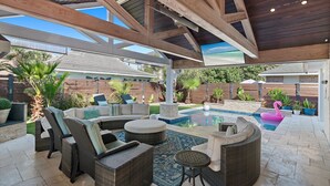 Eine Terrassengruppe im Freien mit Korbmöbeln, einem Pool und einem Flamingo-Schwimmding.