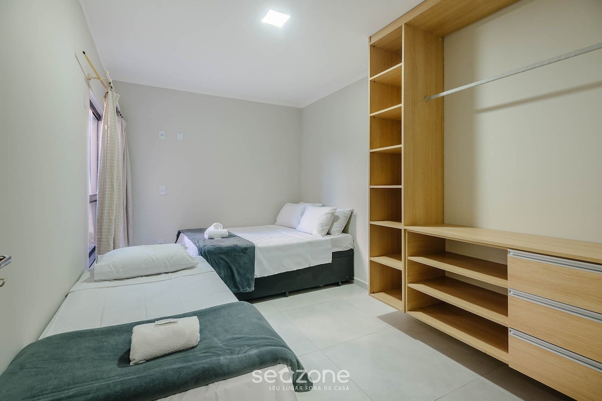 Un dormitorio con dos camas, un armario de madera y un ventanal con cortinas.