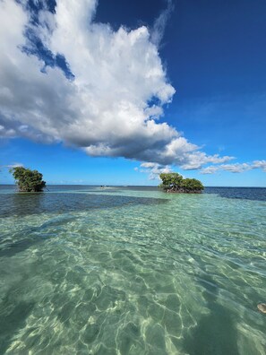A clear view of a tropical beach with two small islands and calm turquoise waters.