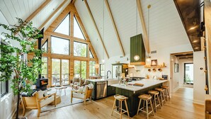 Una cocina amplia con una isla grande, vigas de madera y ventanas espaciosas.