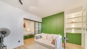 Uma sala de estar moderna com um sofá branco, uma mesa redonda pequena e um ventilador.