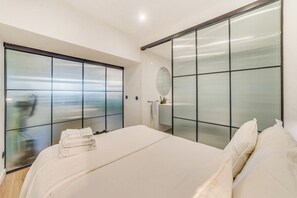 A modern bedroom with a large bed, a sliding glass door, and a mirror on the wall.