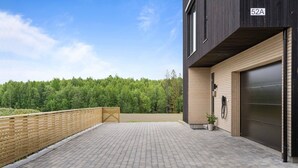 A modern building with a paved driveway, a garage, and a wooden fence. - New and Modern Entire Rental Unit in Ås and Ski Norway (Ås)