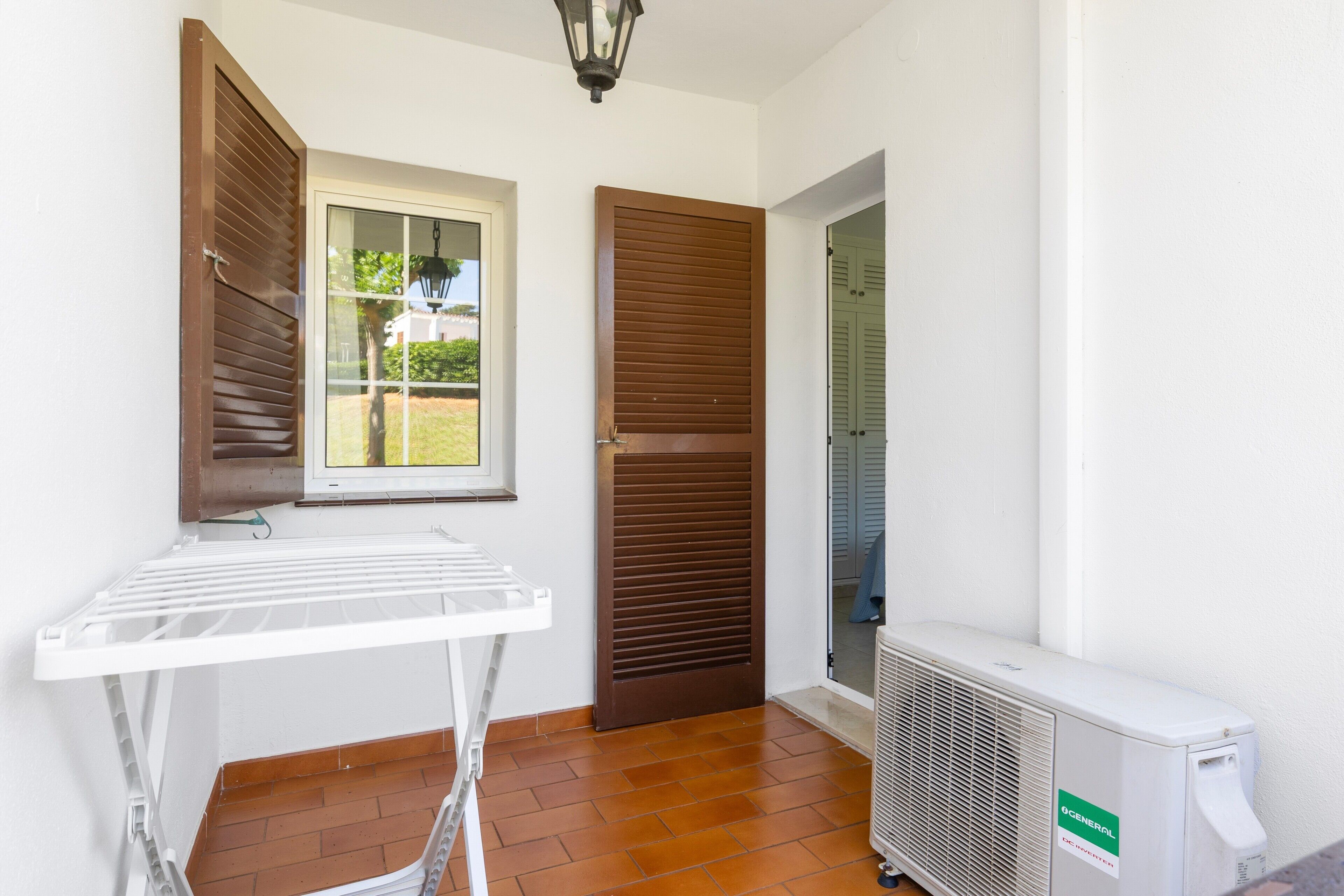Una habitación con ventana, puerta, radiador y un tendedero.
