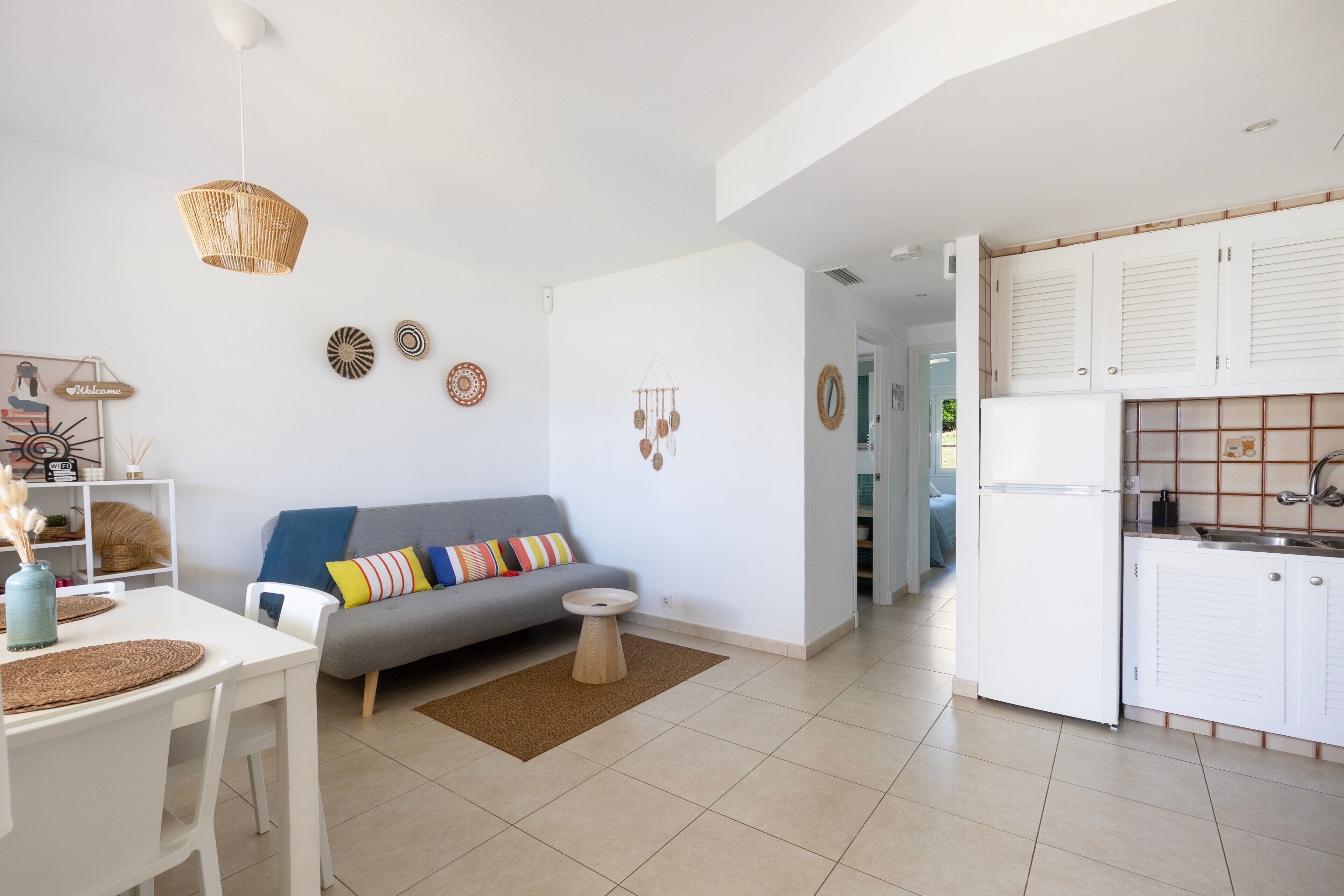 Una sala de estar moderna con un sofá, una mesa de comedor y una cocina con armarios y un refrigerador.