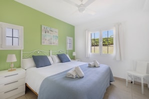 Une chambre à coucher avec un lit, des tables de chevet, une chaise et une fenêtre avec des rideaux.