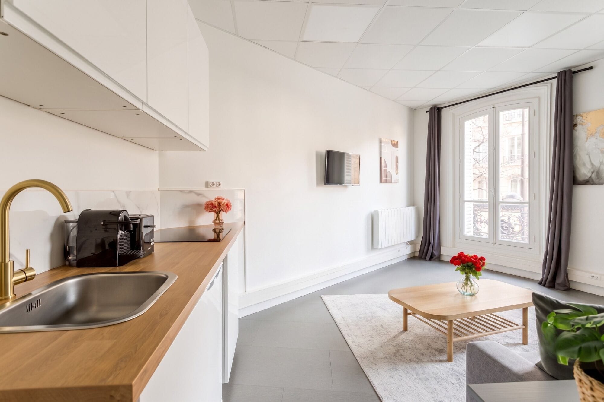 A modern kitchen with a wooden countertop, stainless steel sink, and a coffee machine.