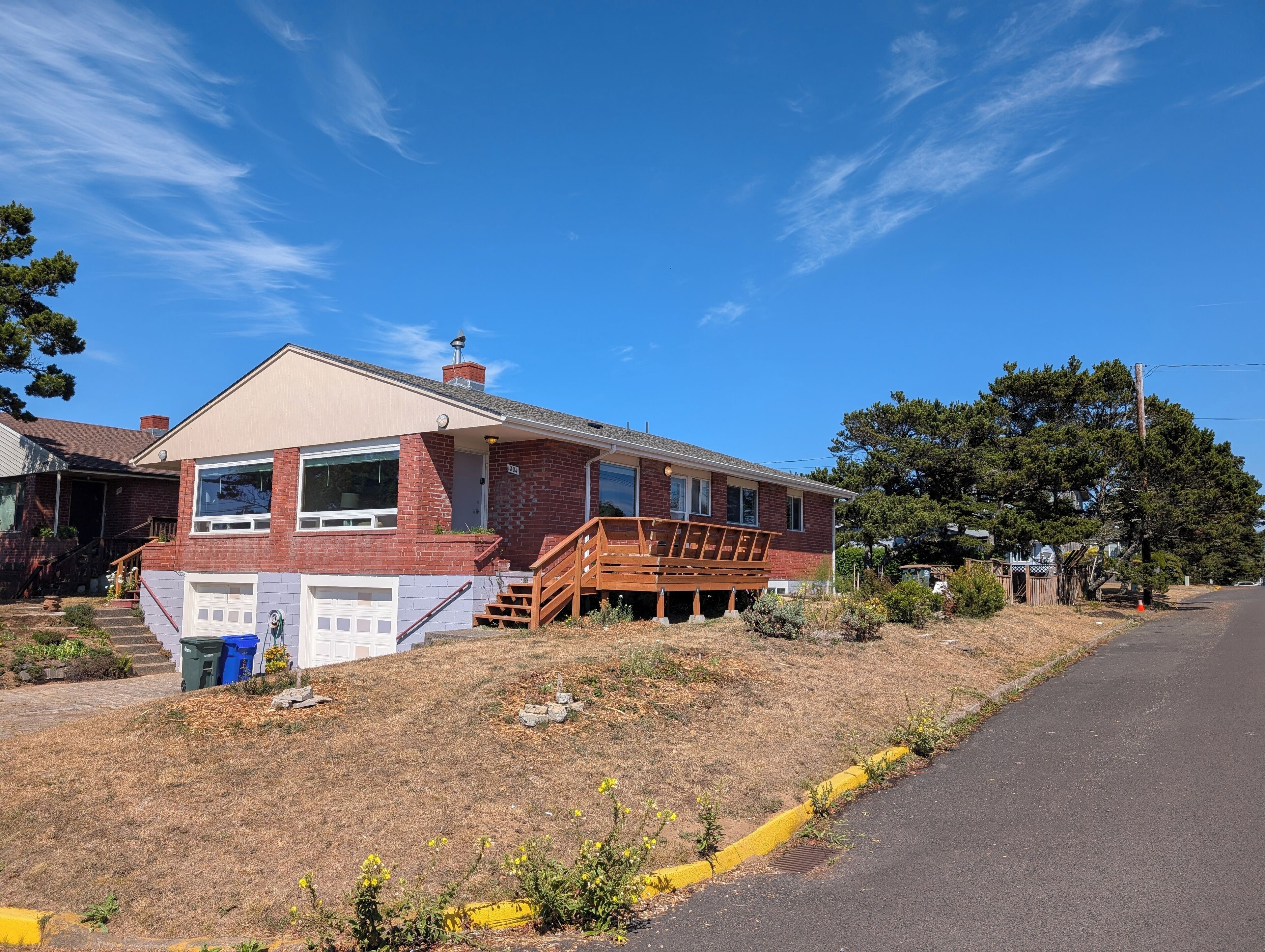 A two-story house with a brick facade, a wooden deck, and a garage.