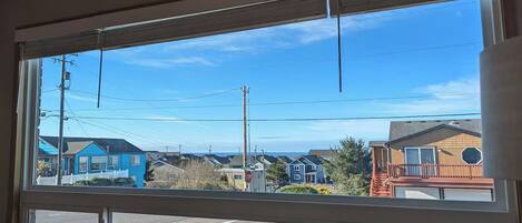 A view through a window with a white frame, featuring a residential area with houses, a stop sign, and power lines.